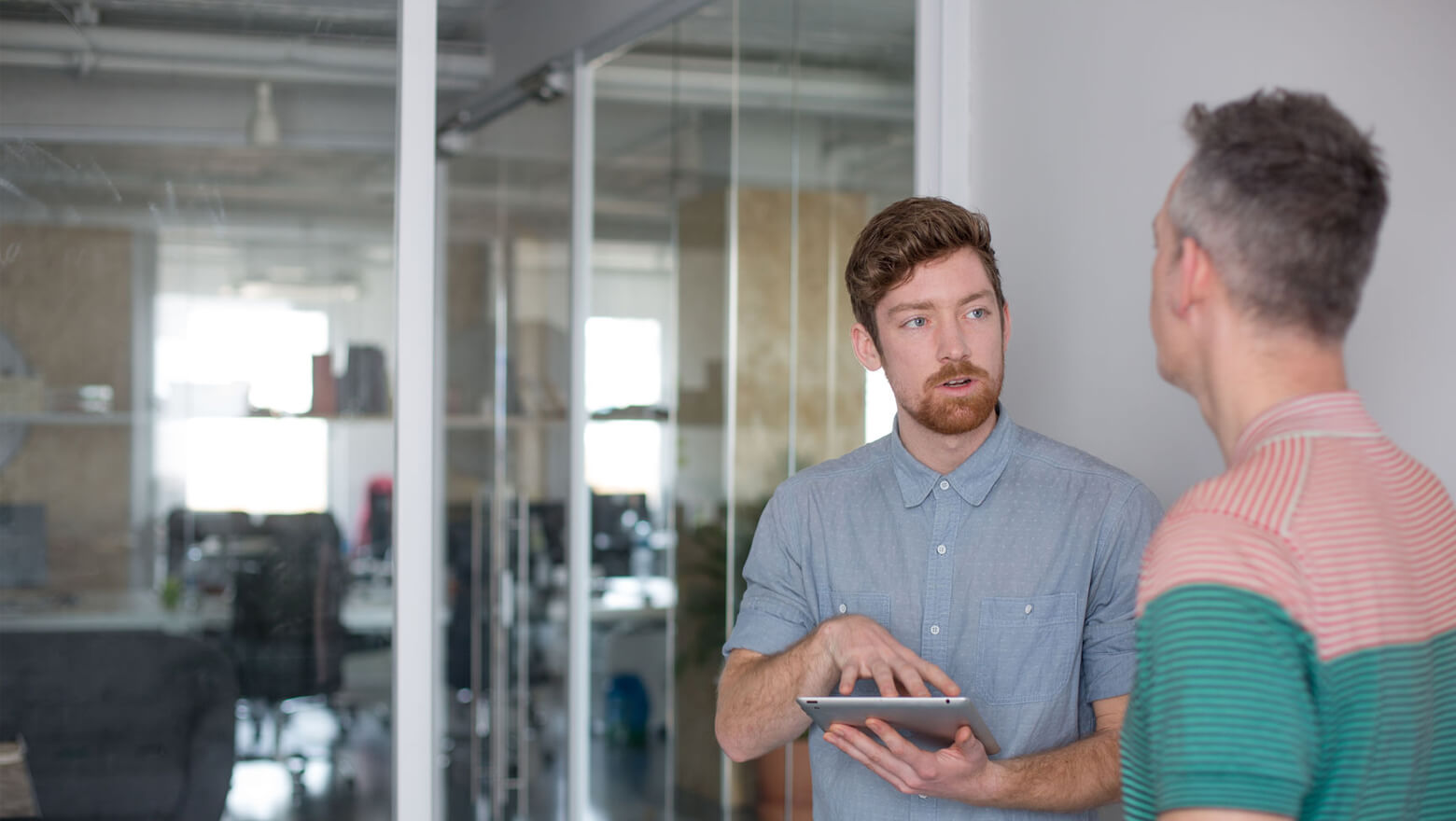 Man holding tablet talking to co-worker