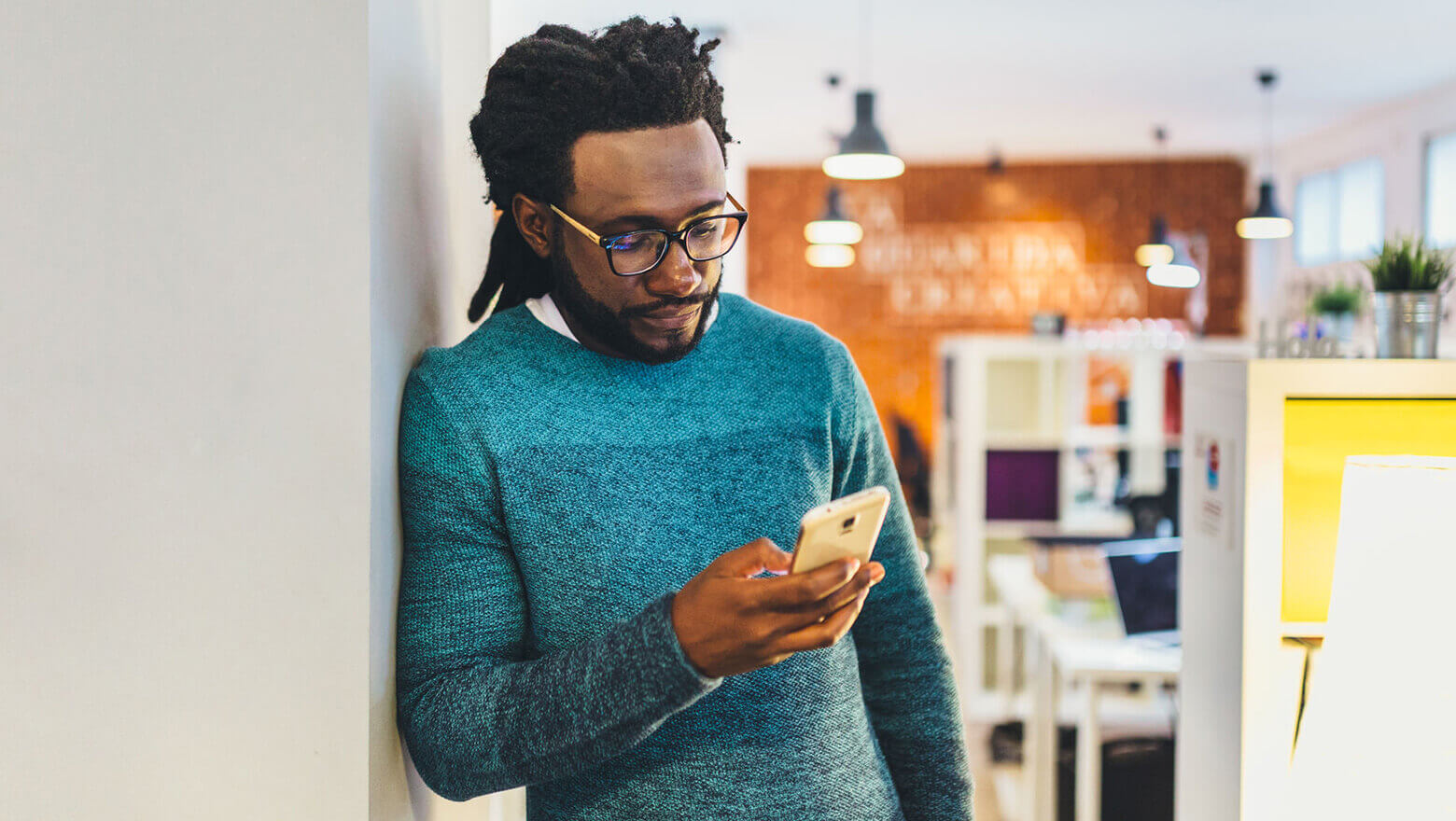 man leaning against wall on his phone