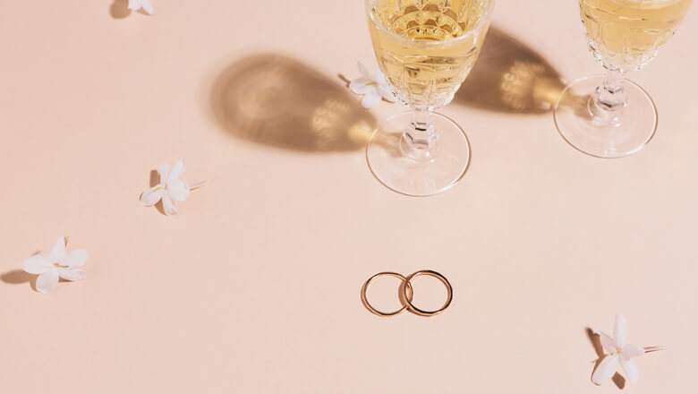 champagne, wedding bands, and flowers