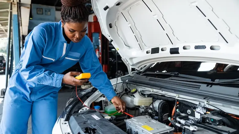 A mechanic checks a car engine.