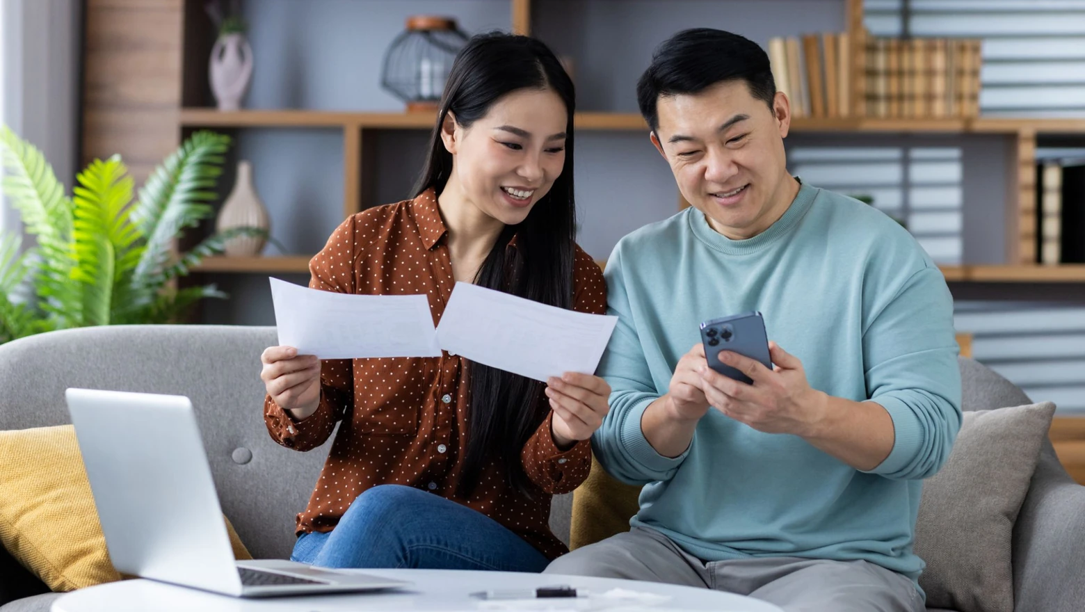 A couple on a sofa reviewing credit score options on a phone, comparing VantageScore and SoFi Coach.