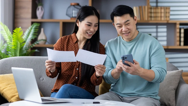 A couple on a sofa reviewing credit score options on a phone, comparing VantageScore and SoFi Coach.