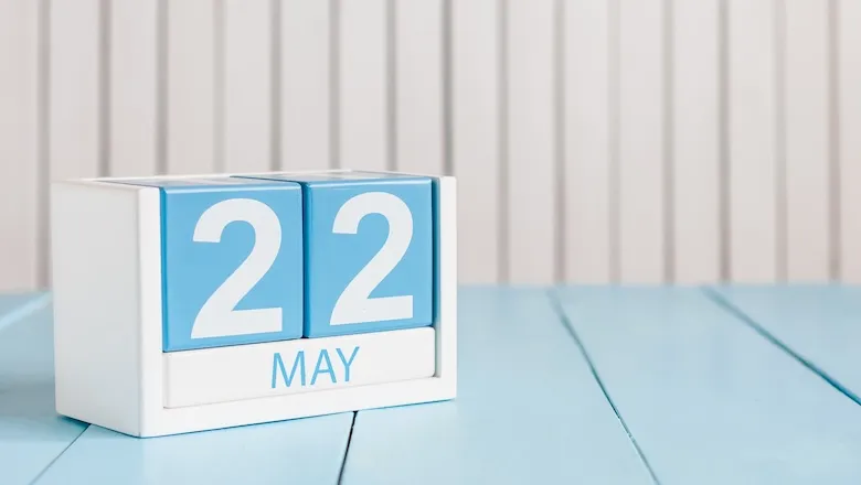 A blue and white wooden calendar displaying the date May 22, which is the day in 2010 known as Bitcoin Pizza Day.