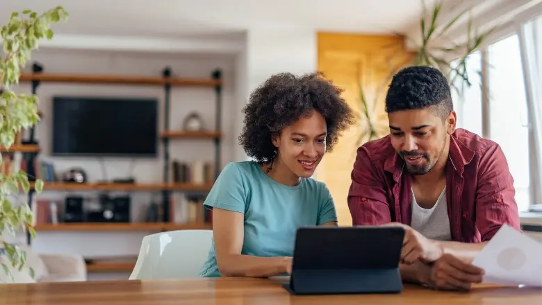 Happy couple sits in front of a laptop planning their retirement portfolio.