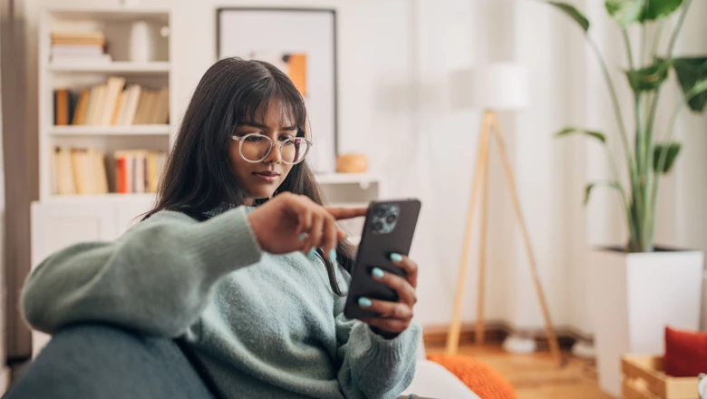 A woman using her phone to research the differences between SoFi Plus and a regular SoFi membership.