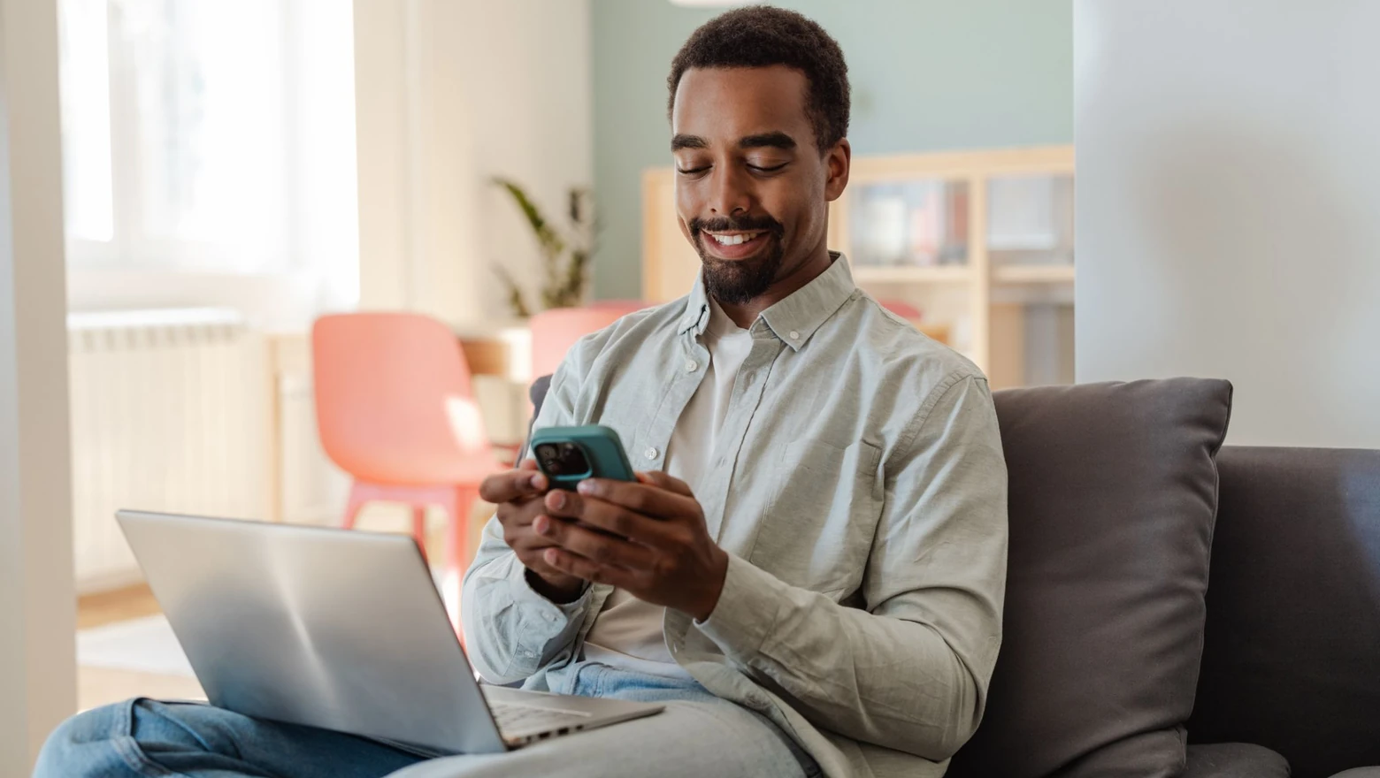 A man sitting on a sofa using his phone to research the Sofi Plus subscription fee.