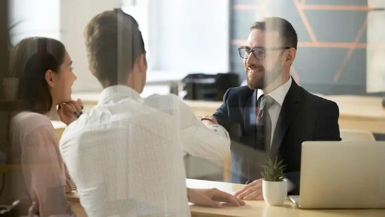 A couple discussing premium banking services with a bank employee at a desk.