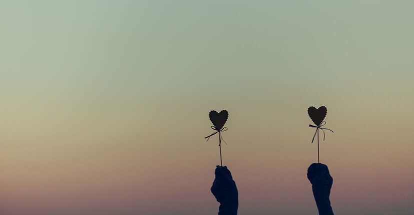 hands holding hearts on sticks