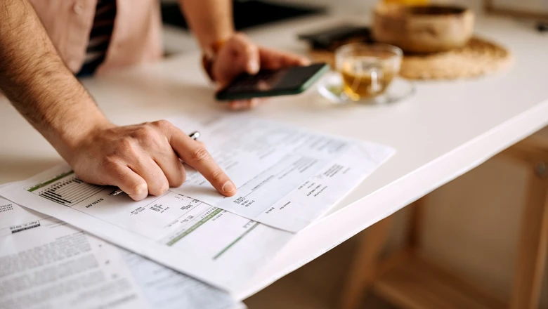 A person reviews personal loan documents and checks their phone, researching prepayment penalty terms.