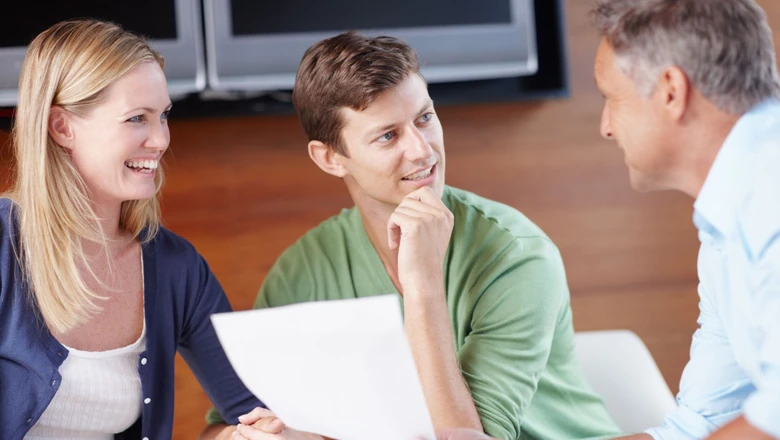 A couple meeting with a financial advisor to review documents and discuss how Fed rate changes affect personal loans.