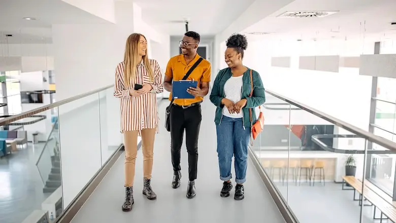 Three people walking in a building at their college intership