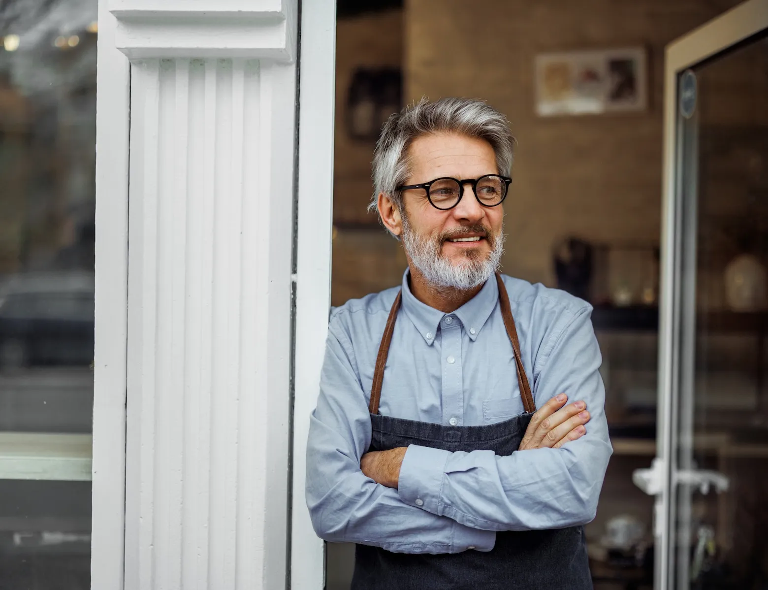 A stressed business owner standing outside of a business planning how to make it through a recession.