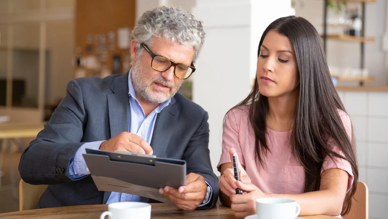 A business owner and her company’s registered agent looking over forms at a small table.