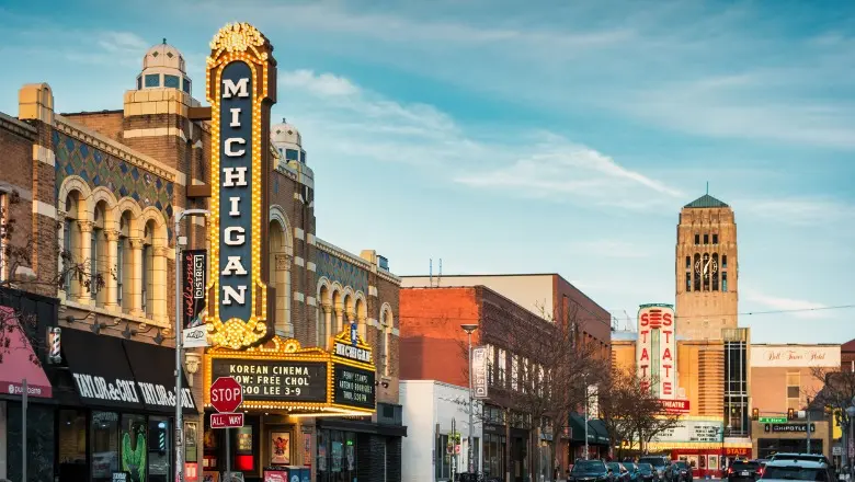 A vibrant street view of the Michigan Theater marquee and other shops in downtown Ann Arbor.