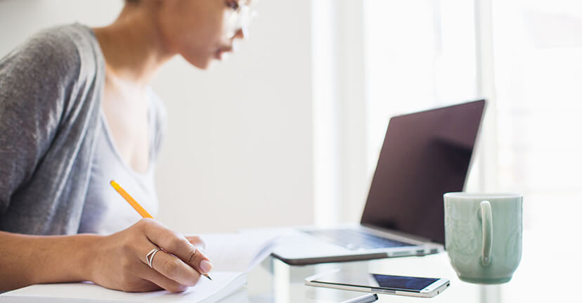 woman taking notes with laptop