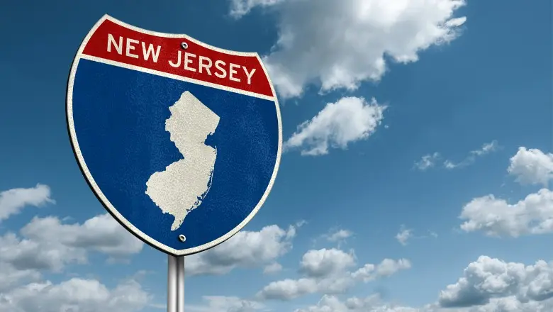 A New Jersey state sign against a blue, cloudy sky.