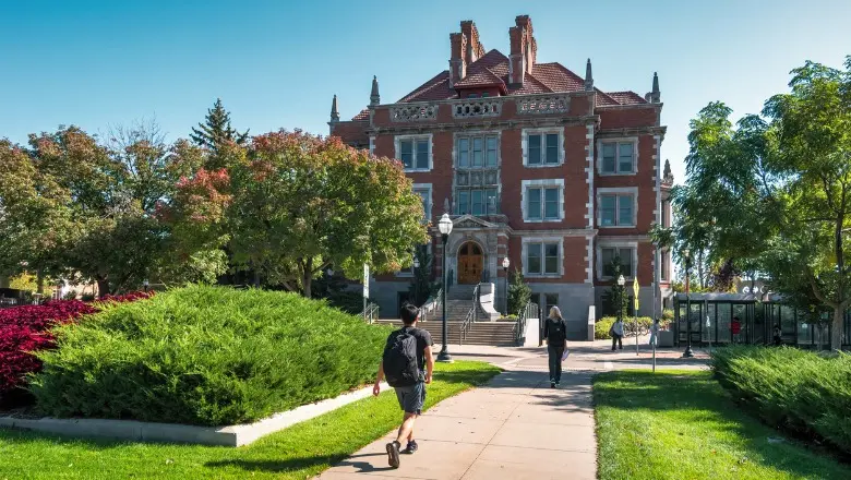 A daytime view of the historic Burton Hall at the University of Minnesota, with students walking on a path.