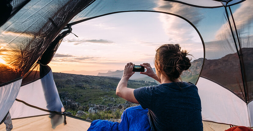 woman with smartphone in tent