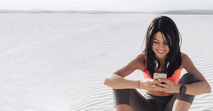 work out woman in sand with smartphone